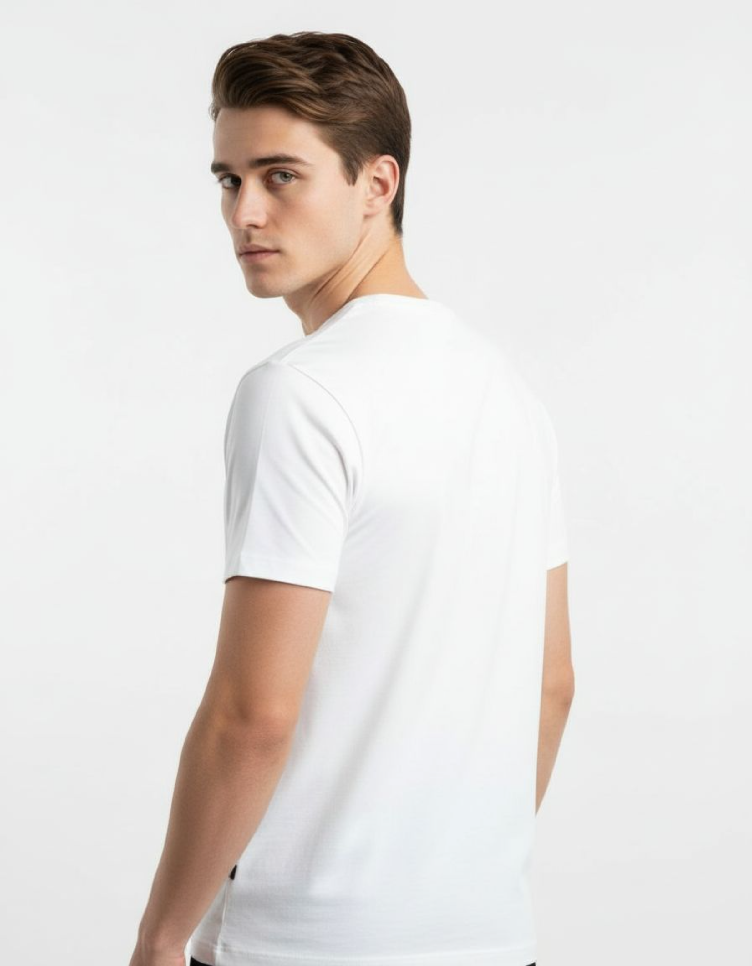 Man wearing a white t-shirt and dark jeans standing against a plain background