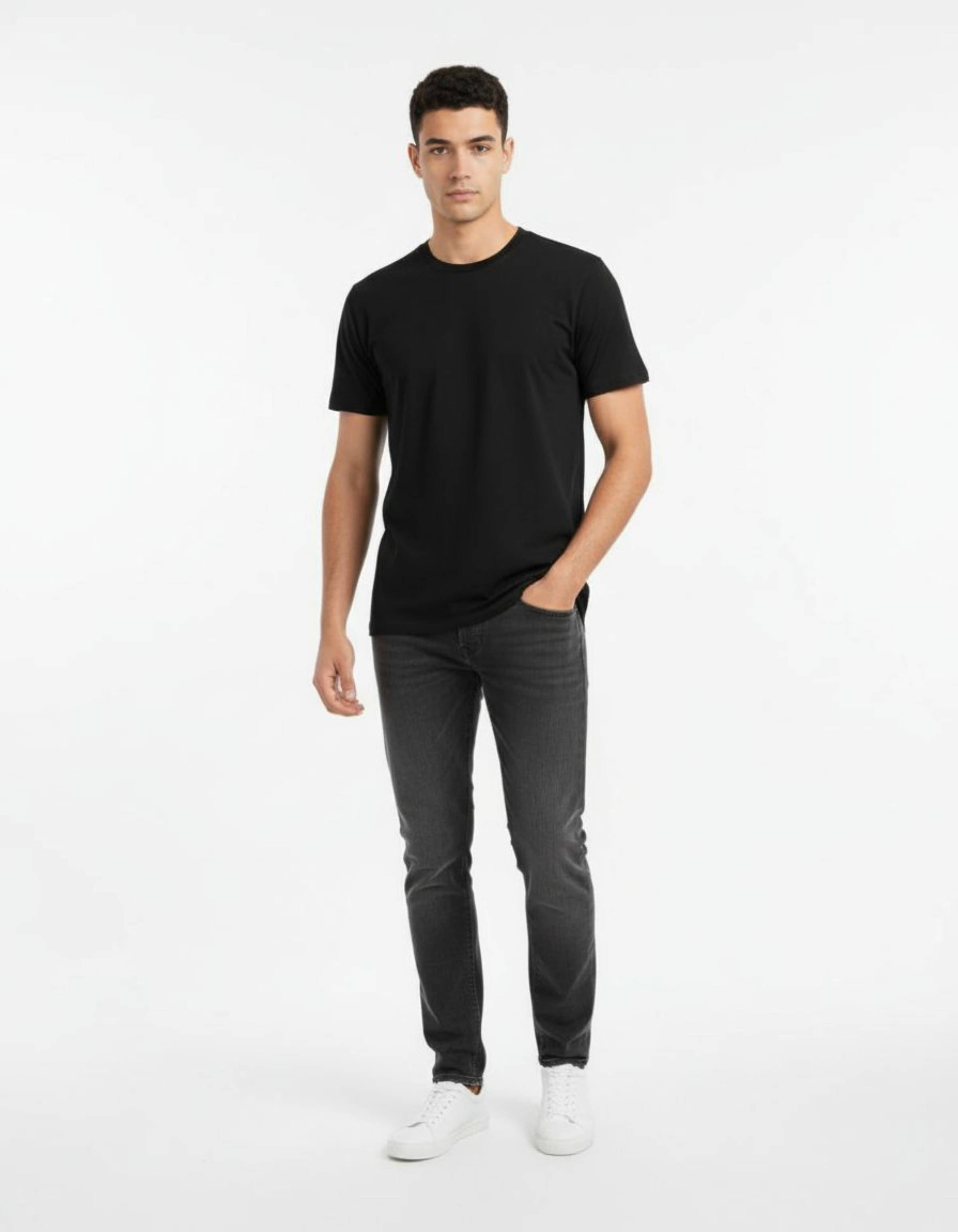 Man wearing a black t-shirt and dark jeans on a white background