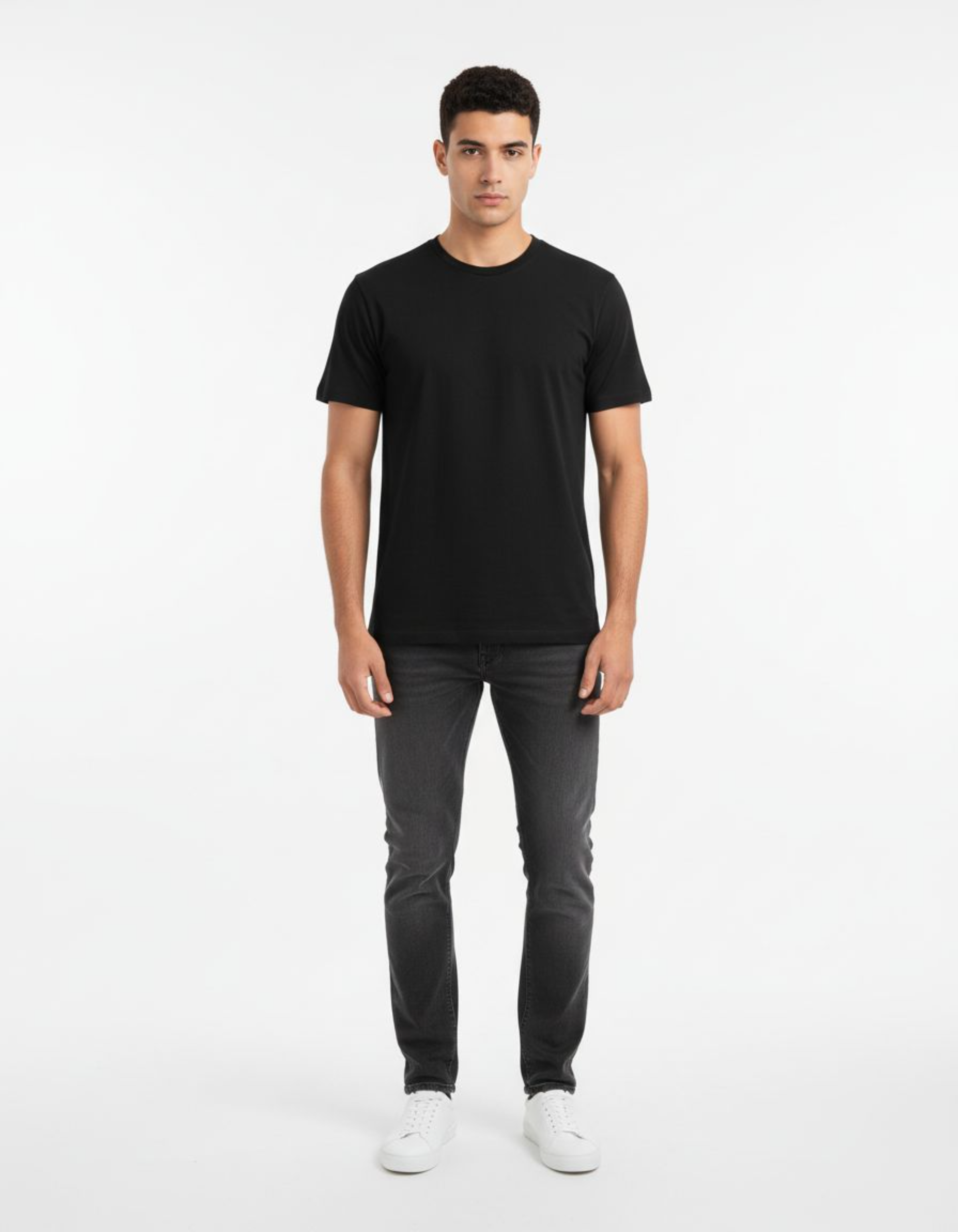 Man wearing a black t-shirt and dark jeans on a white background