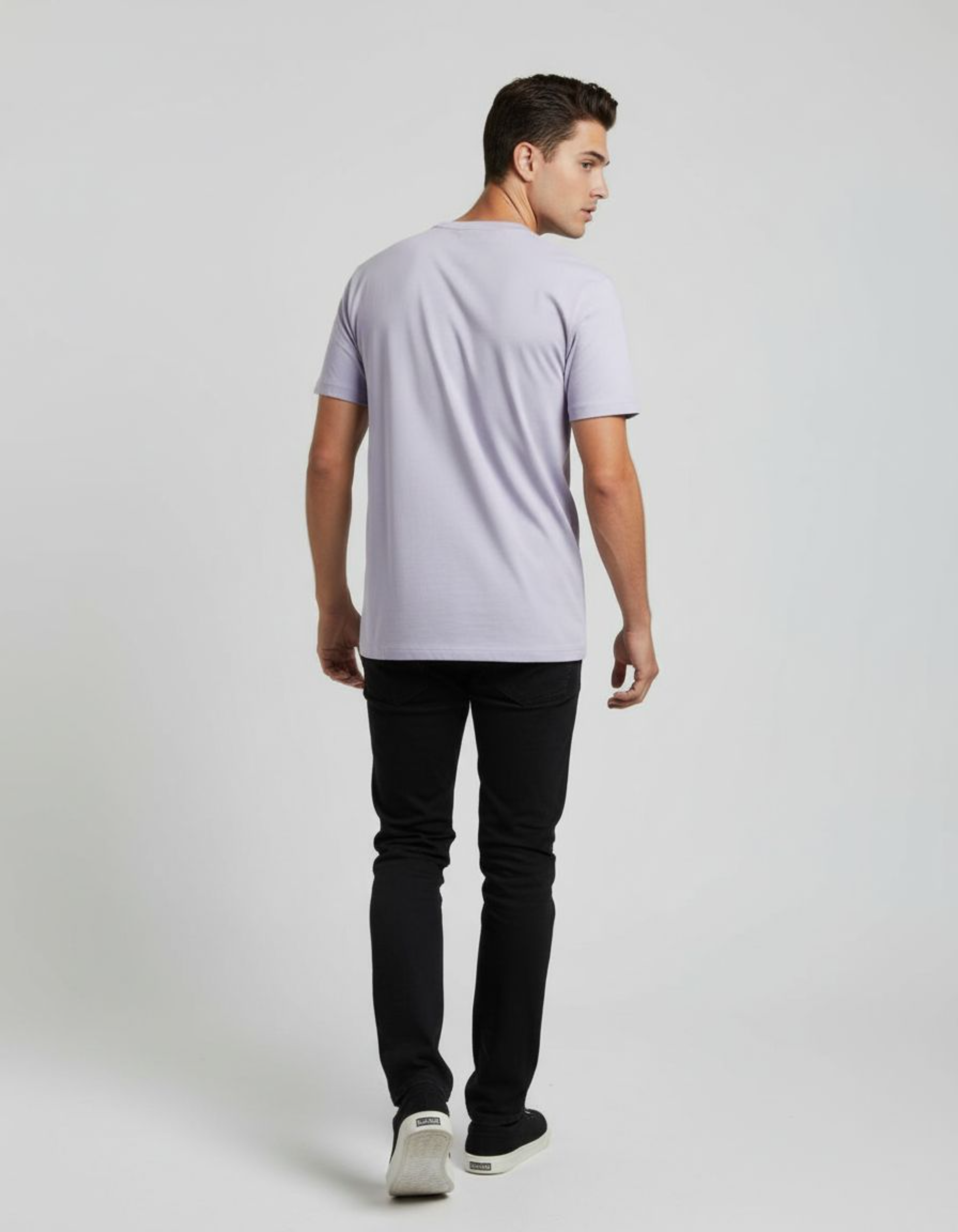 Man wearing a lavender t-shirt and black pants on a white background