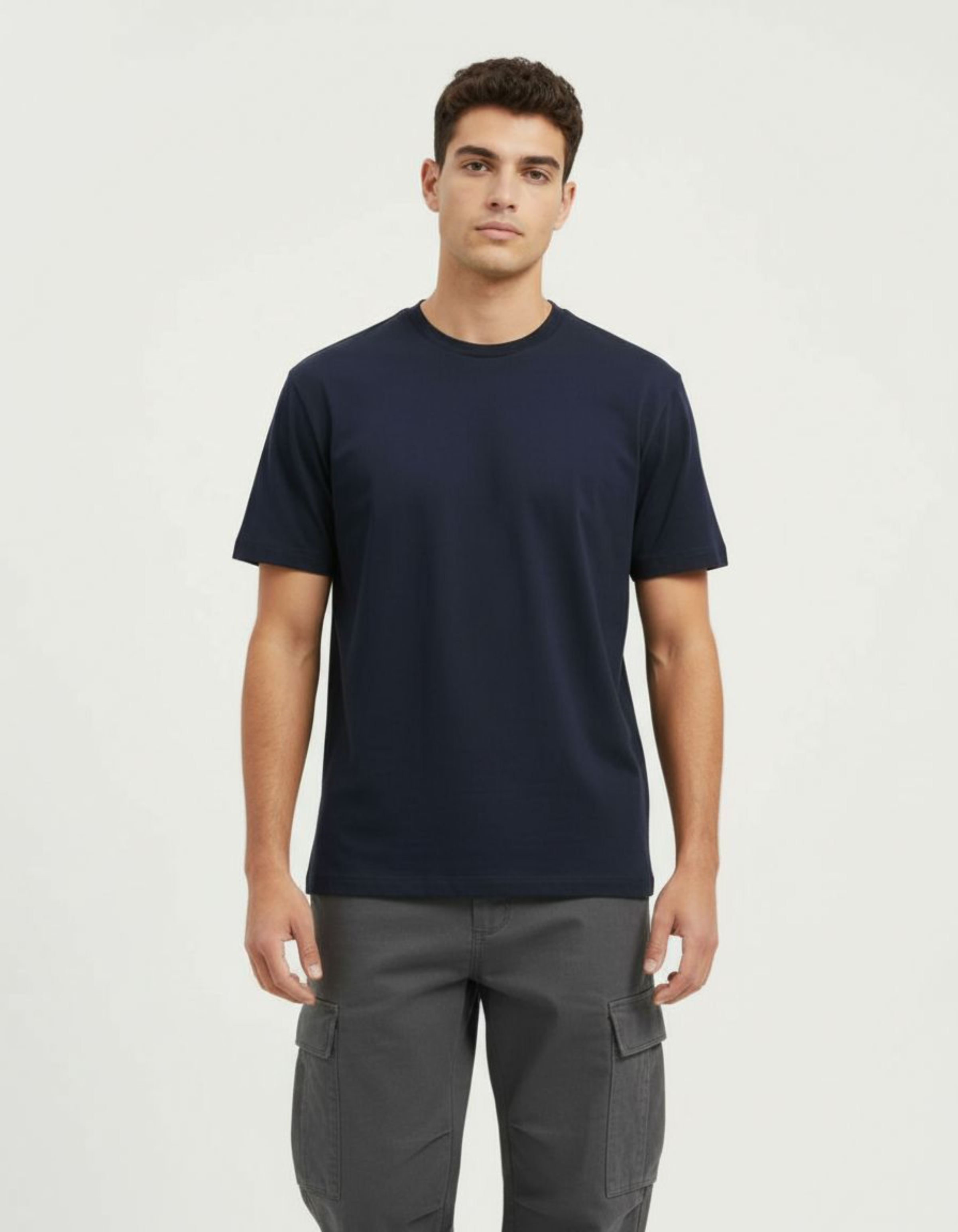 Man wearing a navy t-shirt and gray cargo pants on a white background