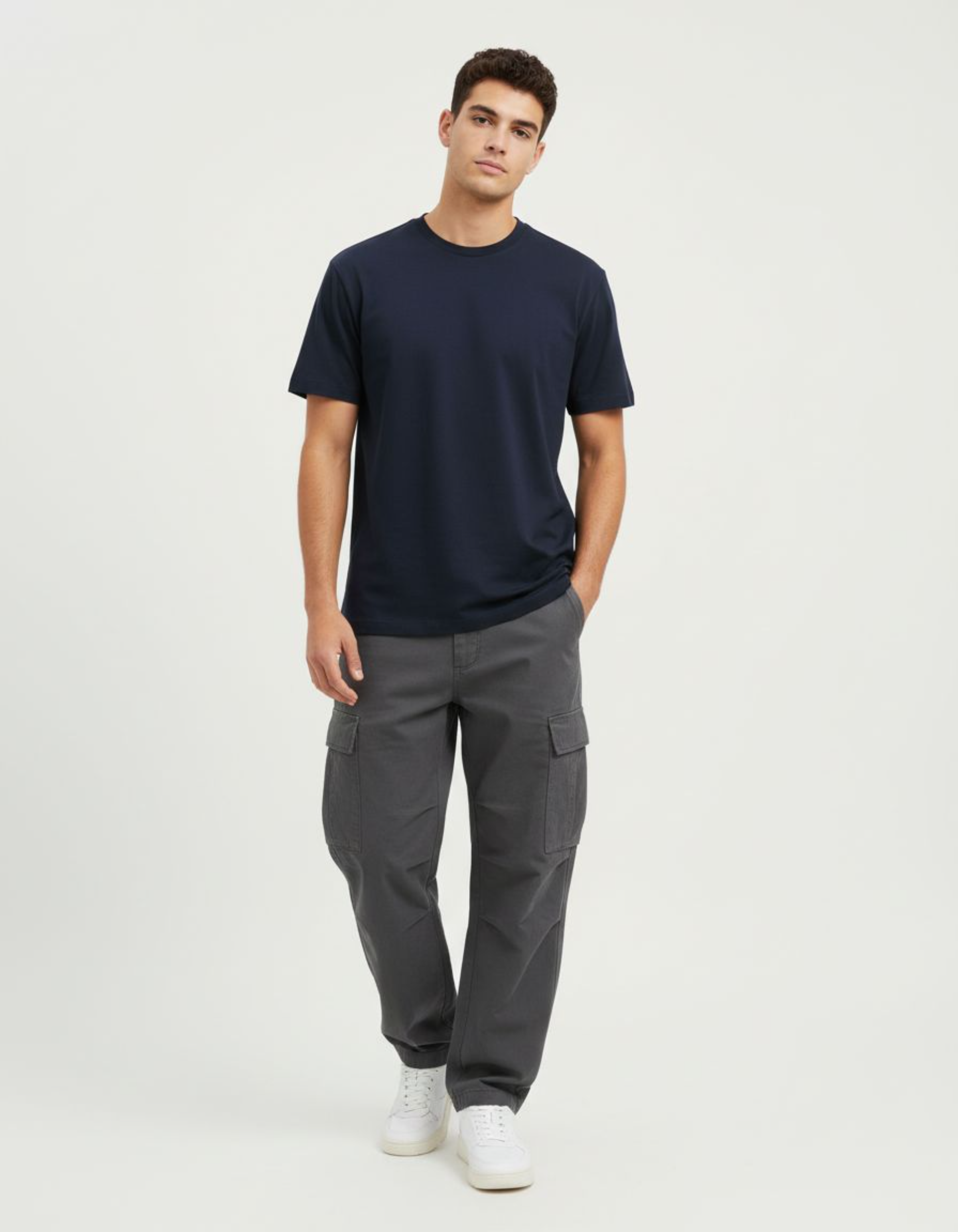 Man wearing a navy t-shirt and gray cargo pants on a white background
