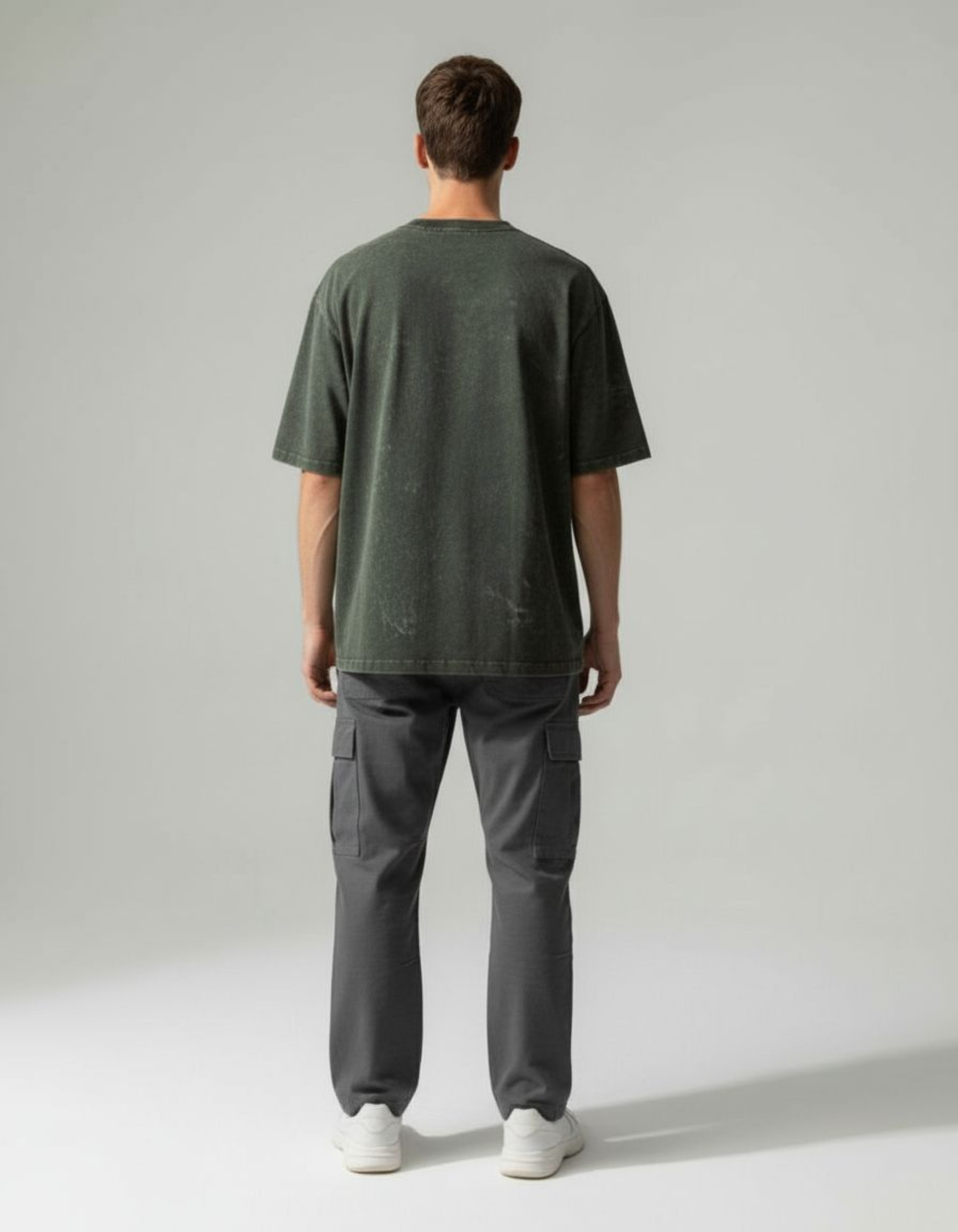 Person wearing a olive green acid washed t-shirt and gray cargo pants on a white background