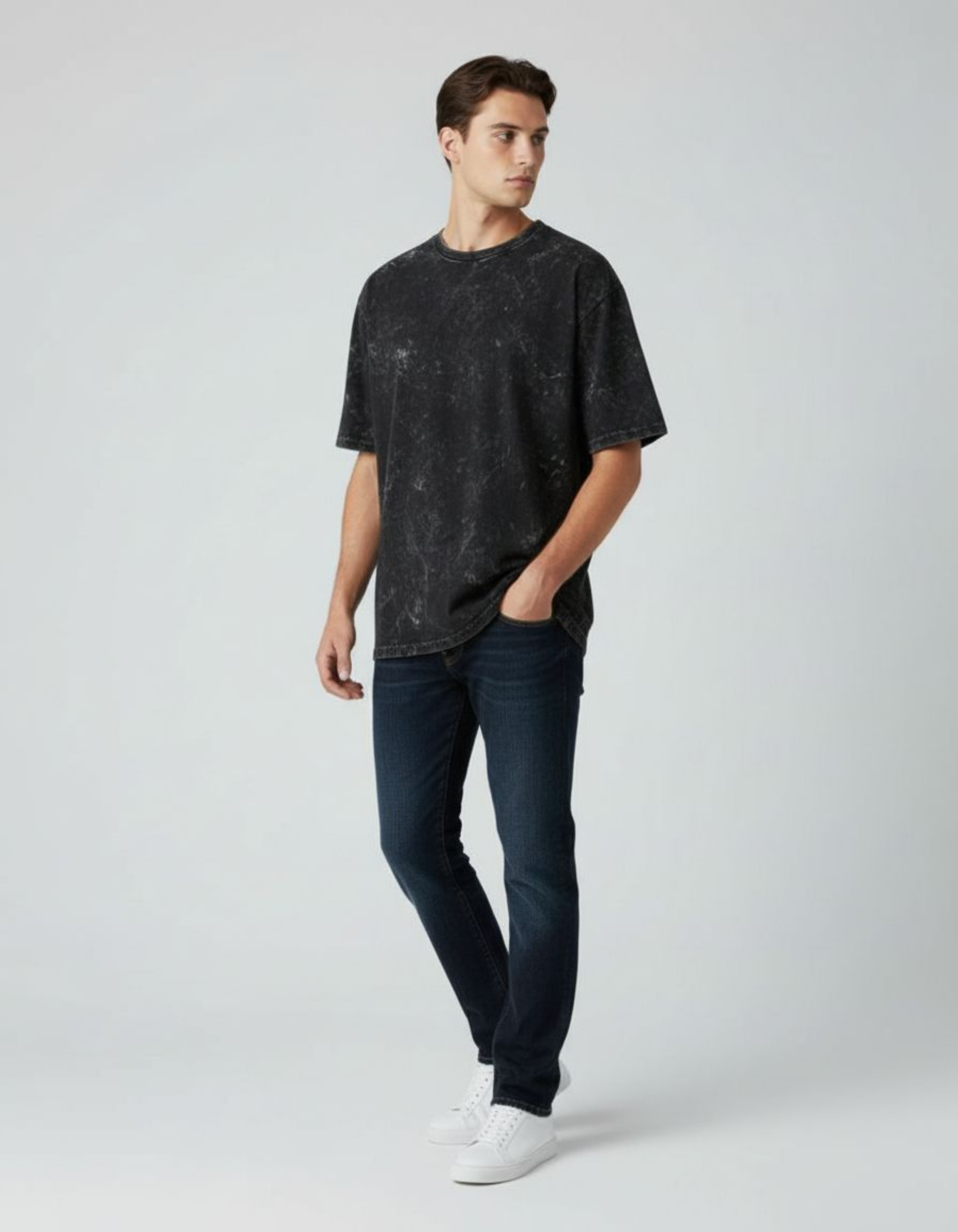Man wearing a black t-shirt and dark jeans on a white background