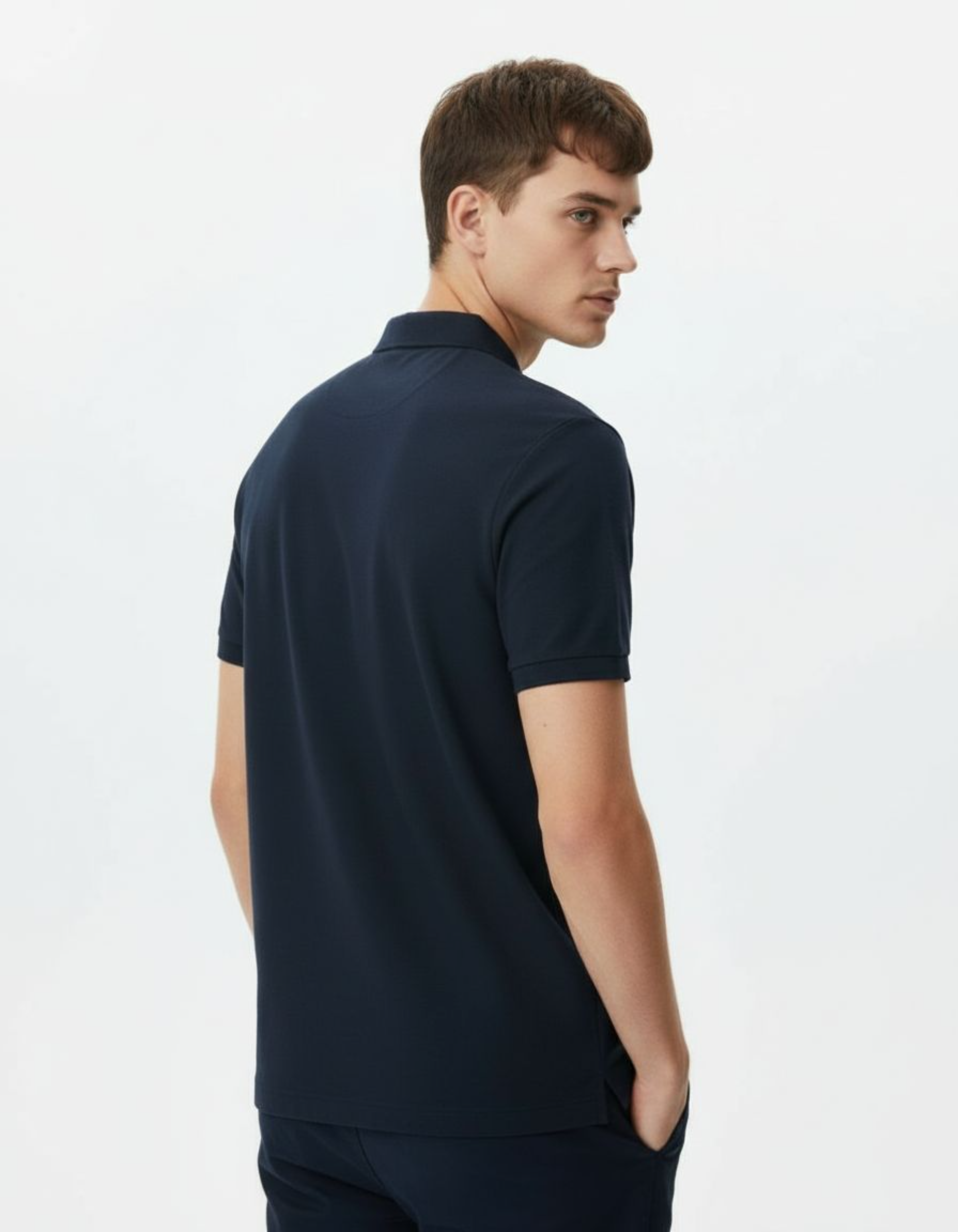 Man wearing a navy polo shirt on a light gray background