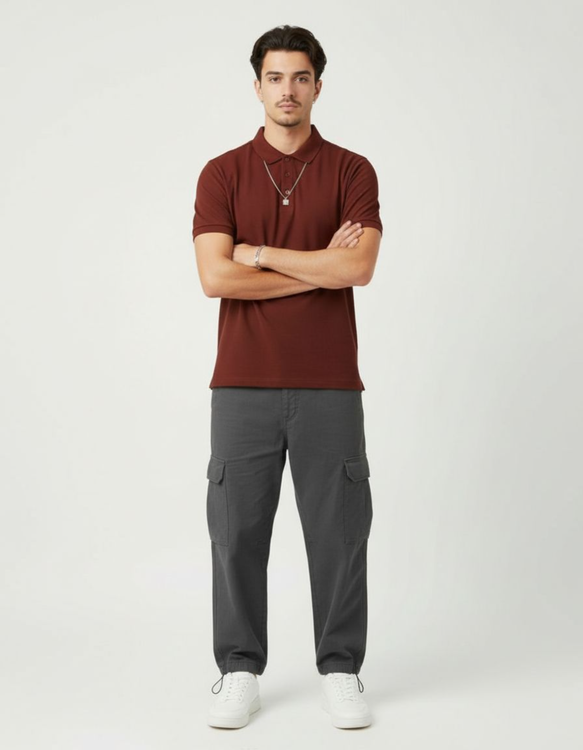 Man wearing a brick red polo shirt and gray pants on a white background